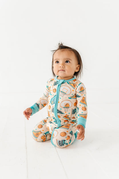 Baby wearing a convertible romper with a sports theme on a white background