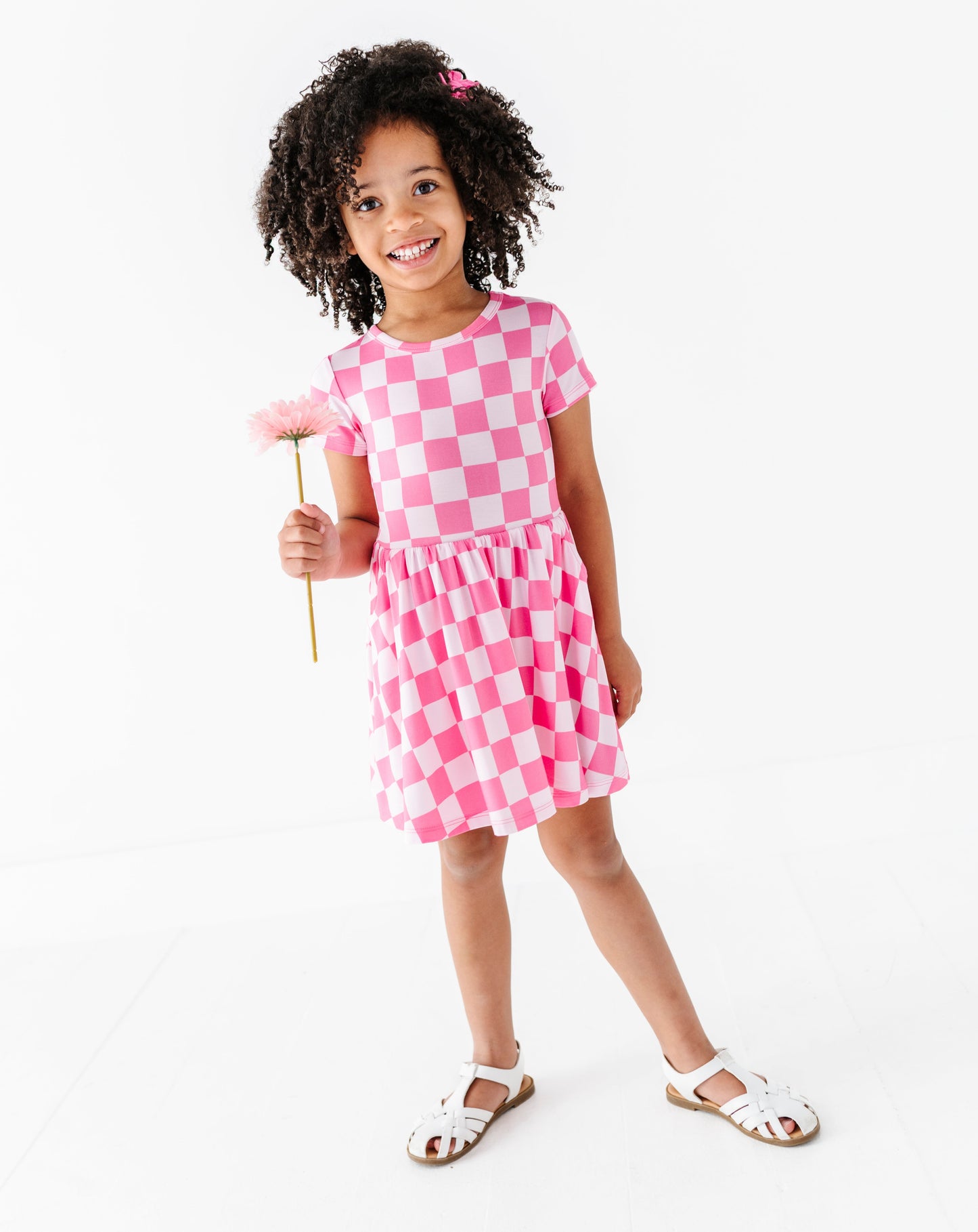 Young girl wearing a pink checkered dress on a white background