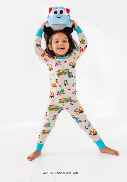 Toddler wearing bamboo pajamas and holding a plush Leo the Truck toy on a white background 