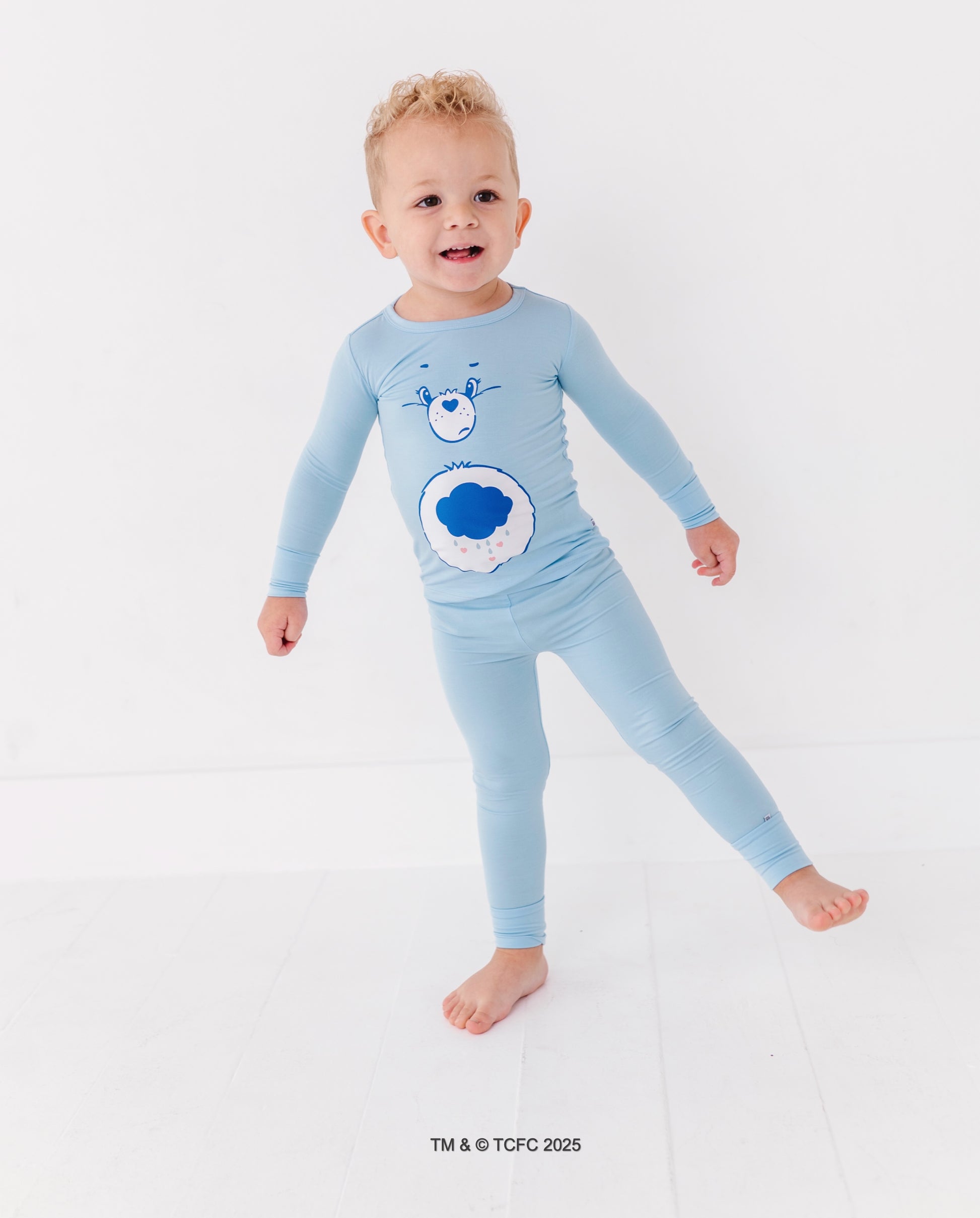 Toddler in light blue Grumpy Bear pajamas featuring iconic cloud belly badge