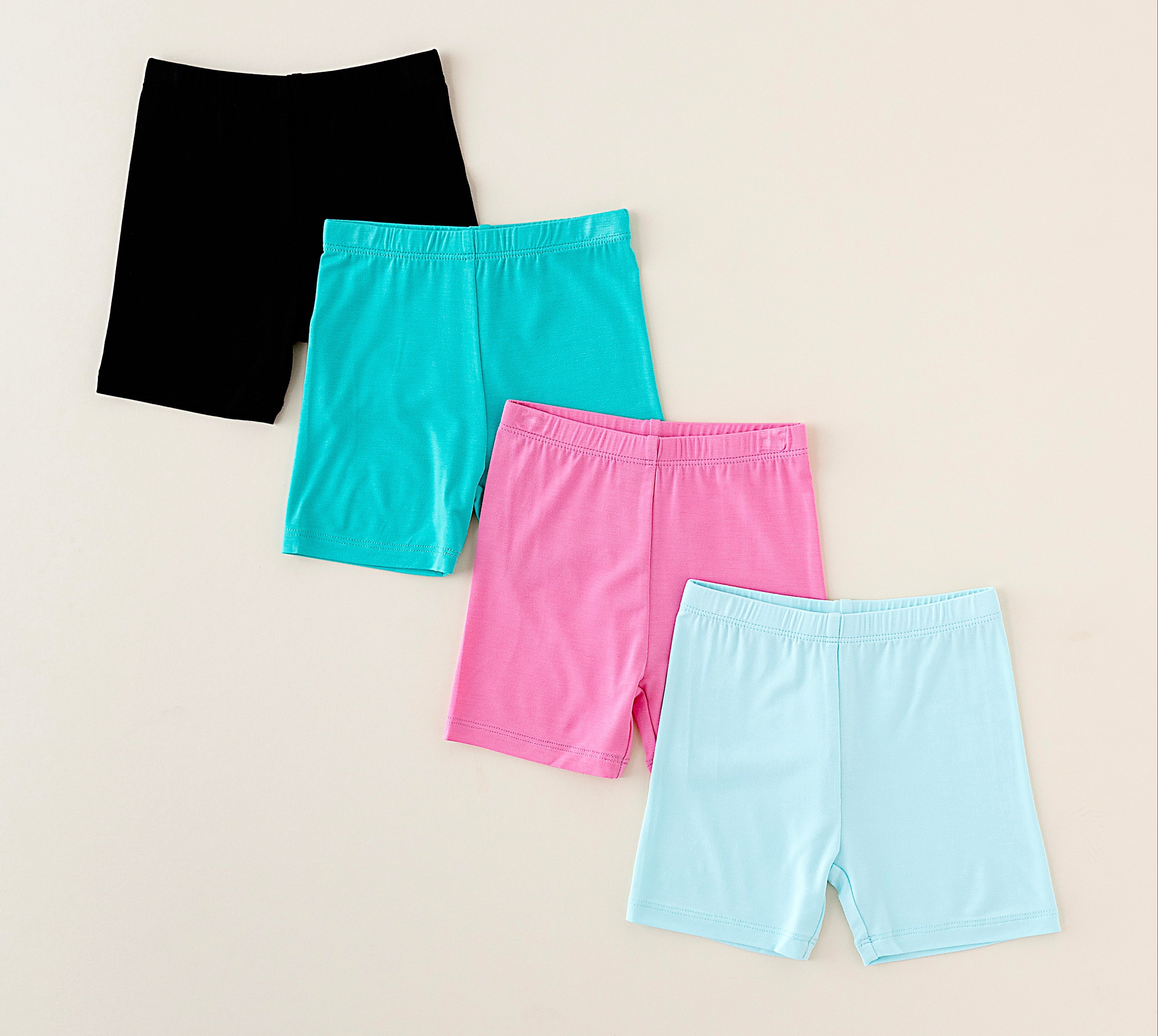 Four pairs of colorful shorts on a beige background