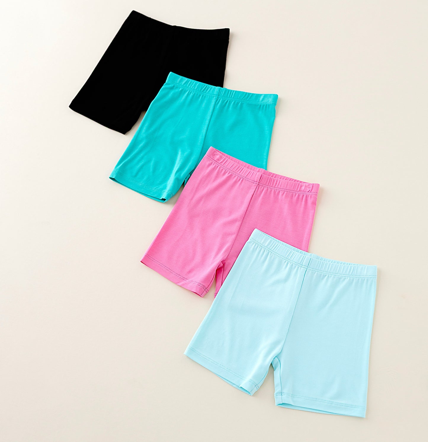 Four pairs of colorful shorts on a beige background