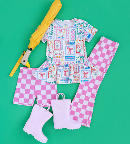 Children's outfit with checkered pants, rain boots, and umbrella on a green background