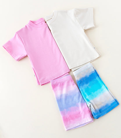 Two shirts, one pink and one white, with a pair of colorful bamboo biker shorts on a light background.