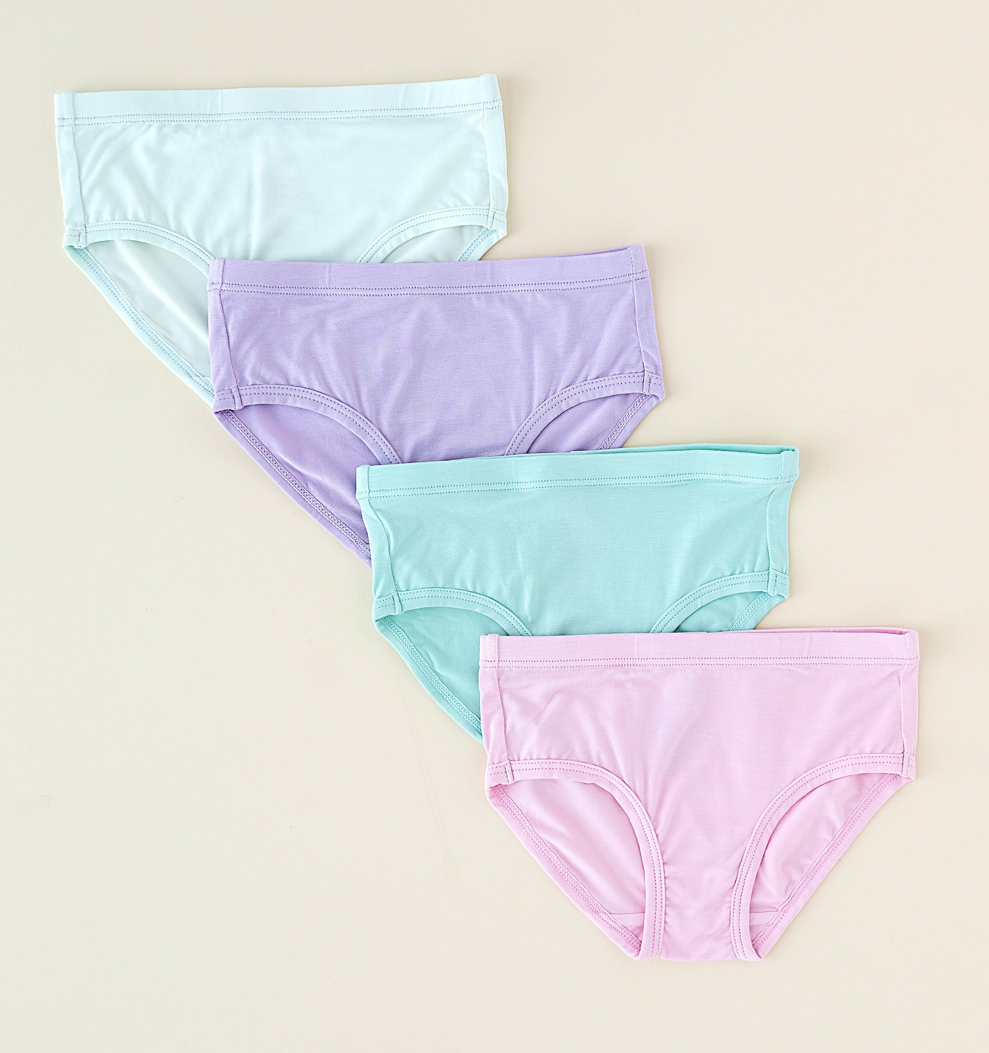 Four pairs of pastel-colored underwear on a beige background