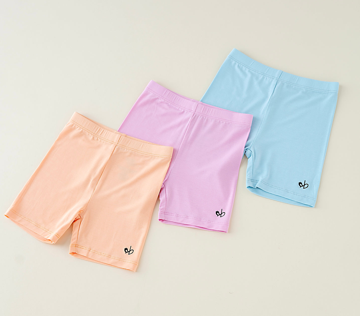 Three pairs of pastel bamboo biker shorts on a beige colored background