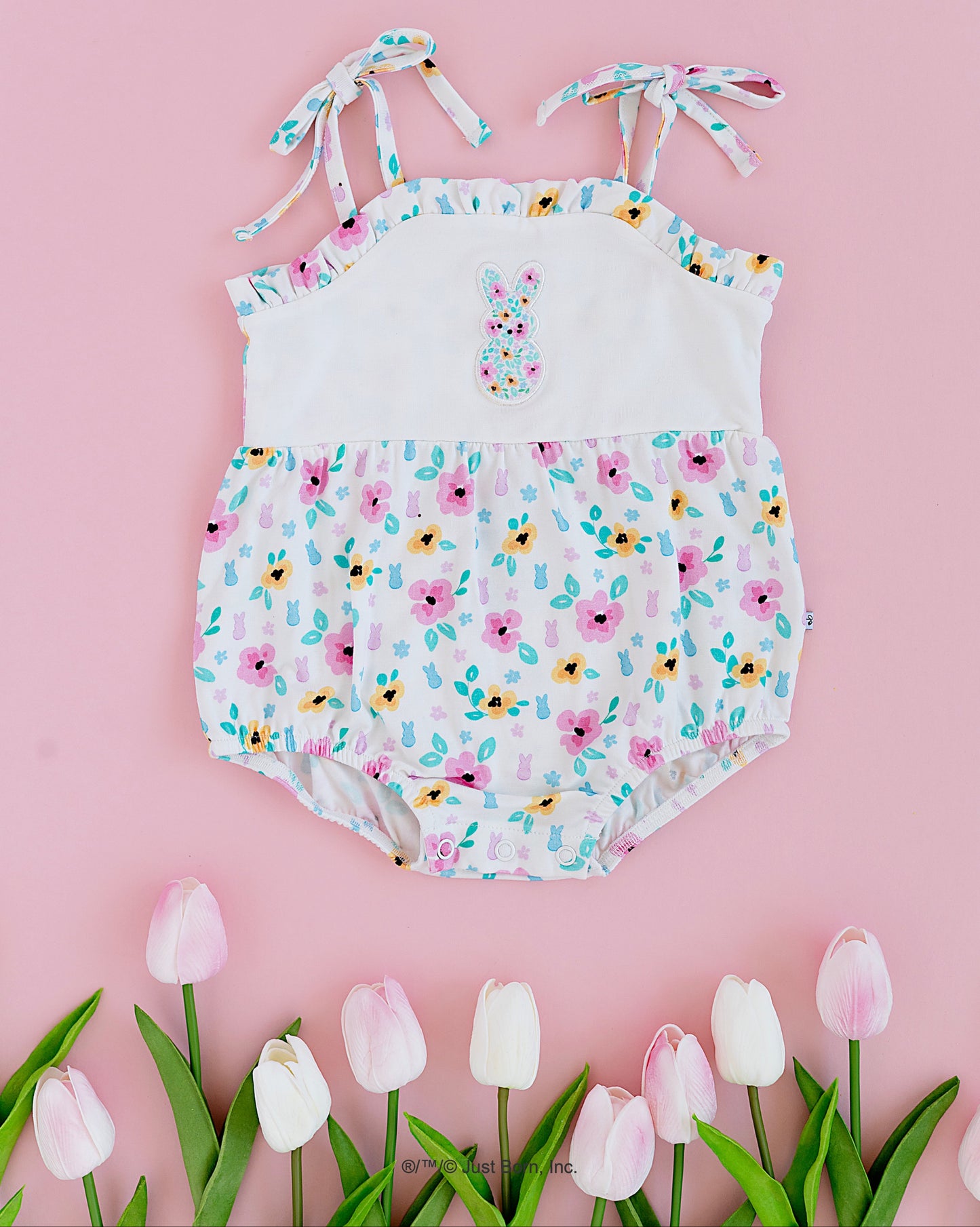 Floral PEEPS® baby romper on a pink background with tulips.