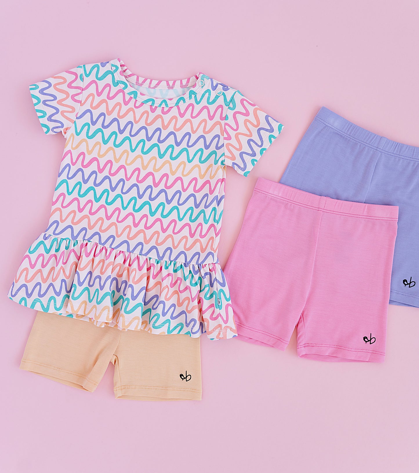 Children's clothing set with a colorful wavy patterned bamboo/cotton top and bamboo biker shorts in pink, purple, and yellow