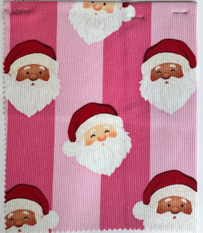 A fabric sample card from Birdie Bean featuring a pink and magenta striped pattern with a repeating Santa Claus face print, displayed on a dark wood surface.