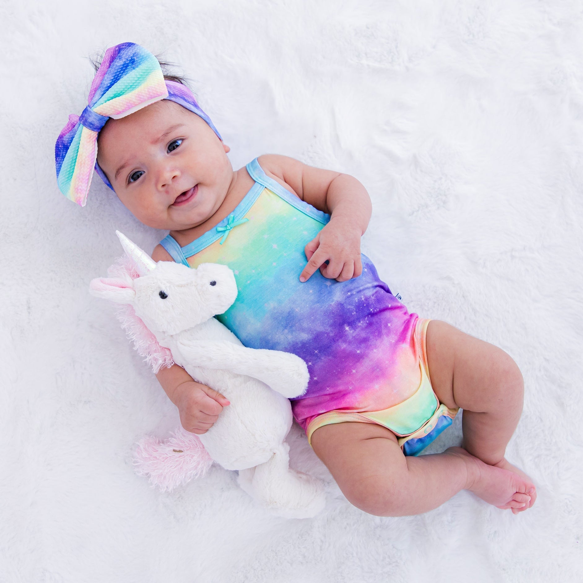 Baby wearing a colorful bow headband with a matching rainbow romper
