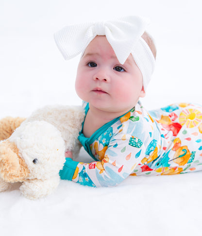 Infant headwrap with white bow paired with colorful romper