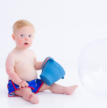 Child wearing Sebastian Swim Shorties with blue shark print and red trim 