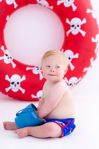 Child wearing Sebastian Swim Shorties with blue shark print playing in sand bucket