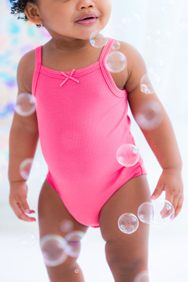 Baby wearing pink ribbed bamboo bodysuit tank