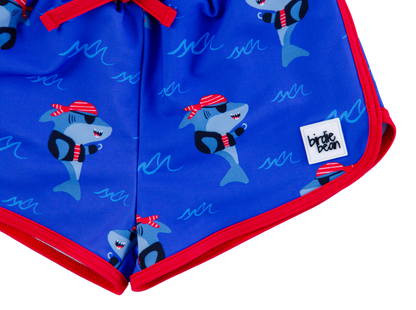 Sebastian Swim Shorties flat lay featuring blue shark print with red trim and small Birdie Bean logo