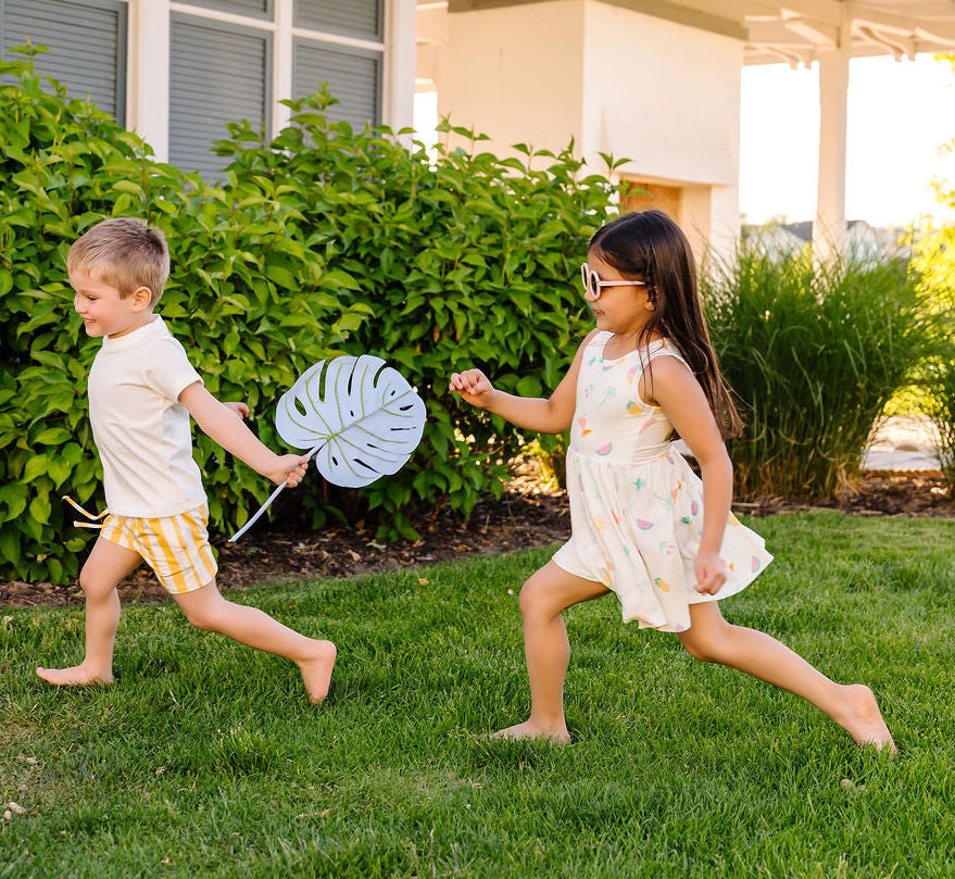 Two children playing in a garden with a house in the background