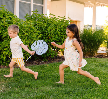 Two children playing in a garden with a house in the background