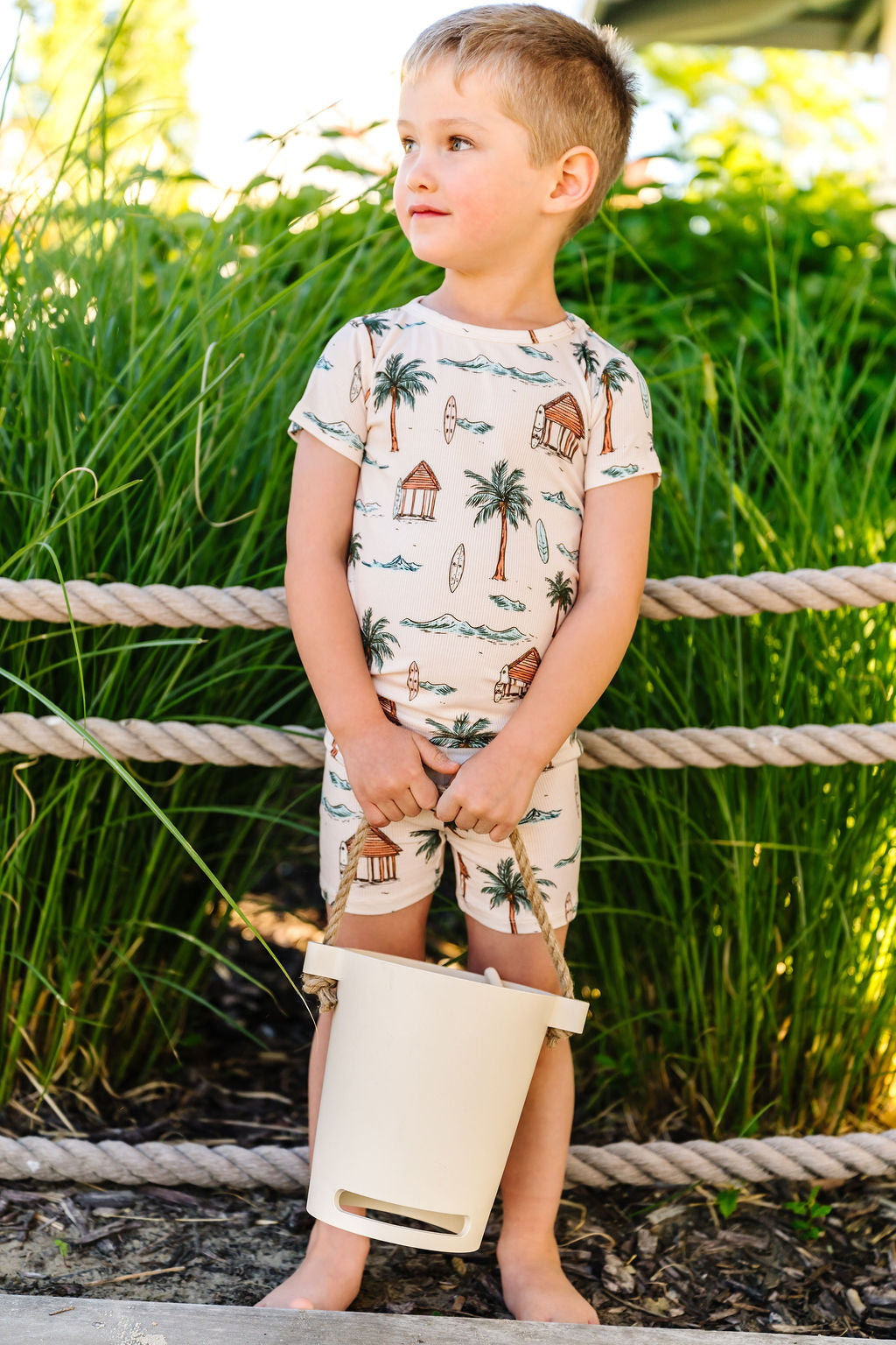 Child wearing a tropical-themed outfit standing outdoors with greenery in the background
