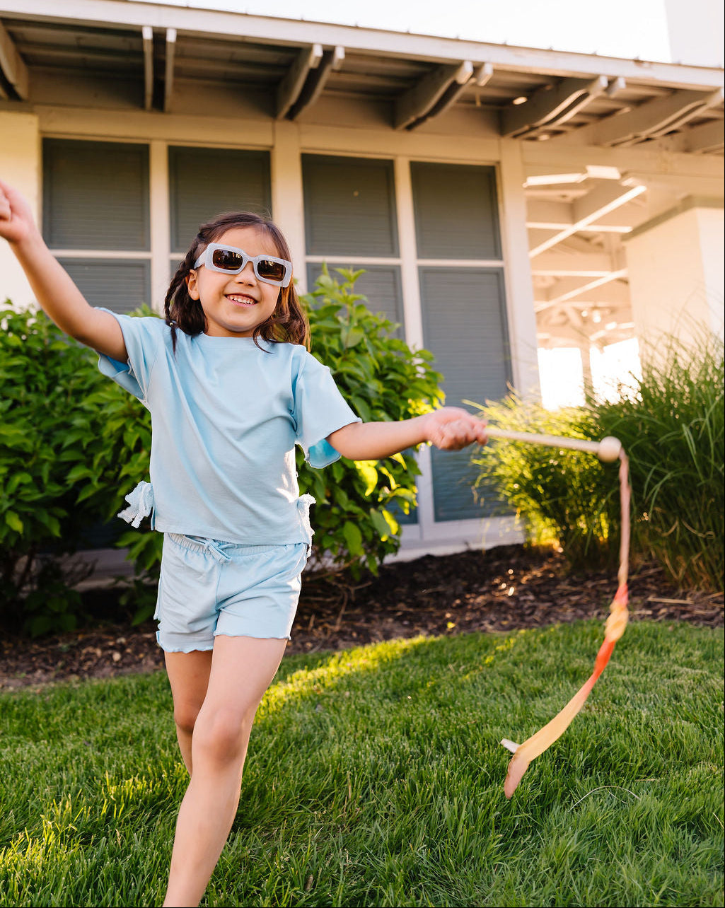 Child playing with a ribbon outdoors in front of a house