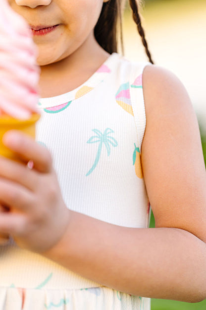 Child wearing a sleeveless dress with palm tree design outdoors