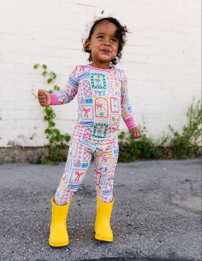 Child wearing a colorful outfit with patterns and yellow rain boots standing on a street.