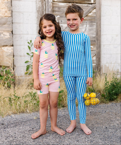 Two children in pajamas standing in front of a rustic wooden building.