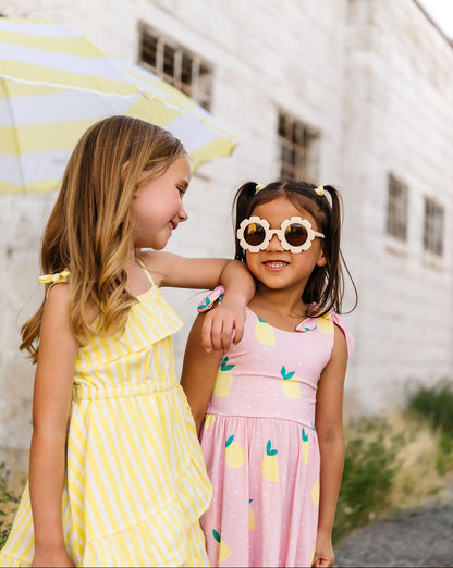 Two young girls in colorful dresses standing outdoors with a white building in the background.