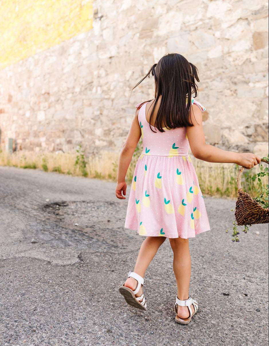 Child in a pink dress walking on a road with a textured wall in the background
