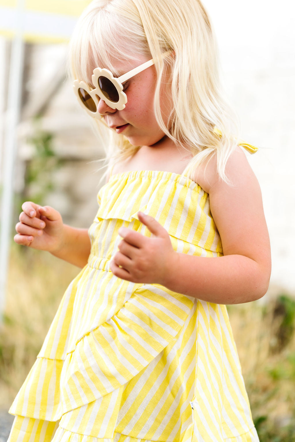 Child wearing a yellow striped dress and sunglasses outdoors