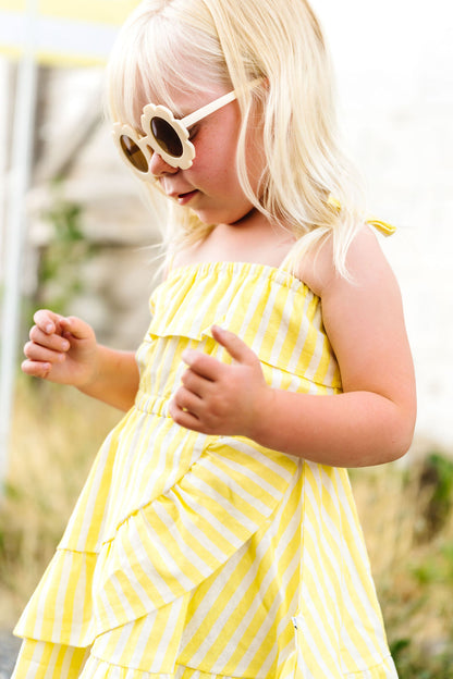 Child wearing a yellow striped dress and sunglasses outdoors