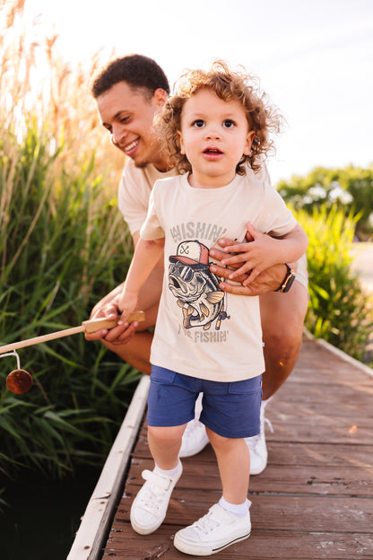 Man holding a child on a wooden dock with nature in the background