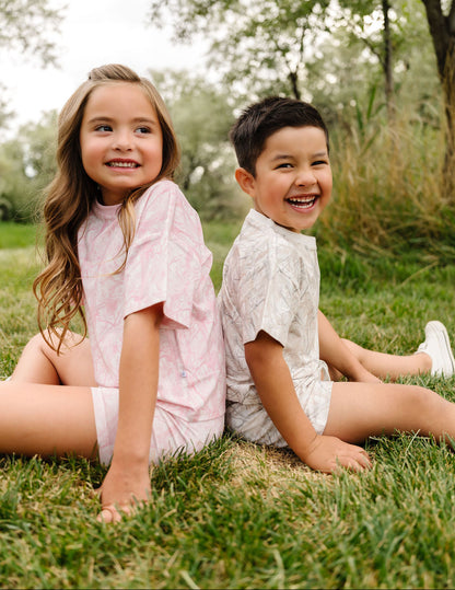 Two children sitting on grass with trees in the background