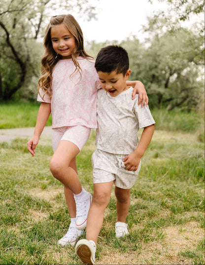 Two children walking together in a grassy outdoor setting