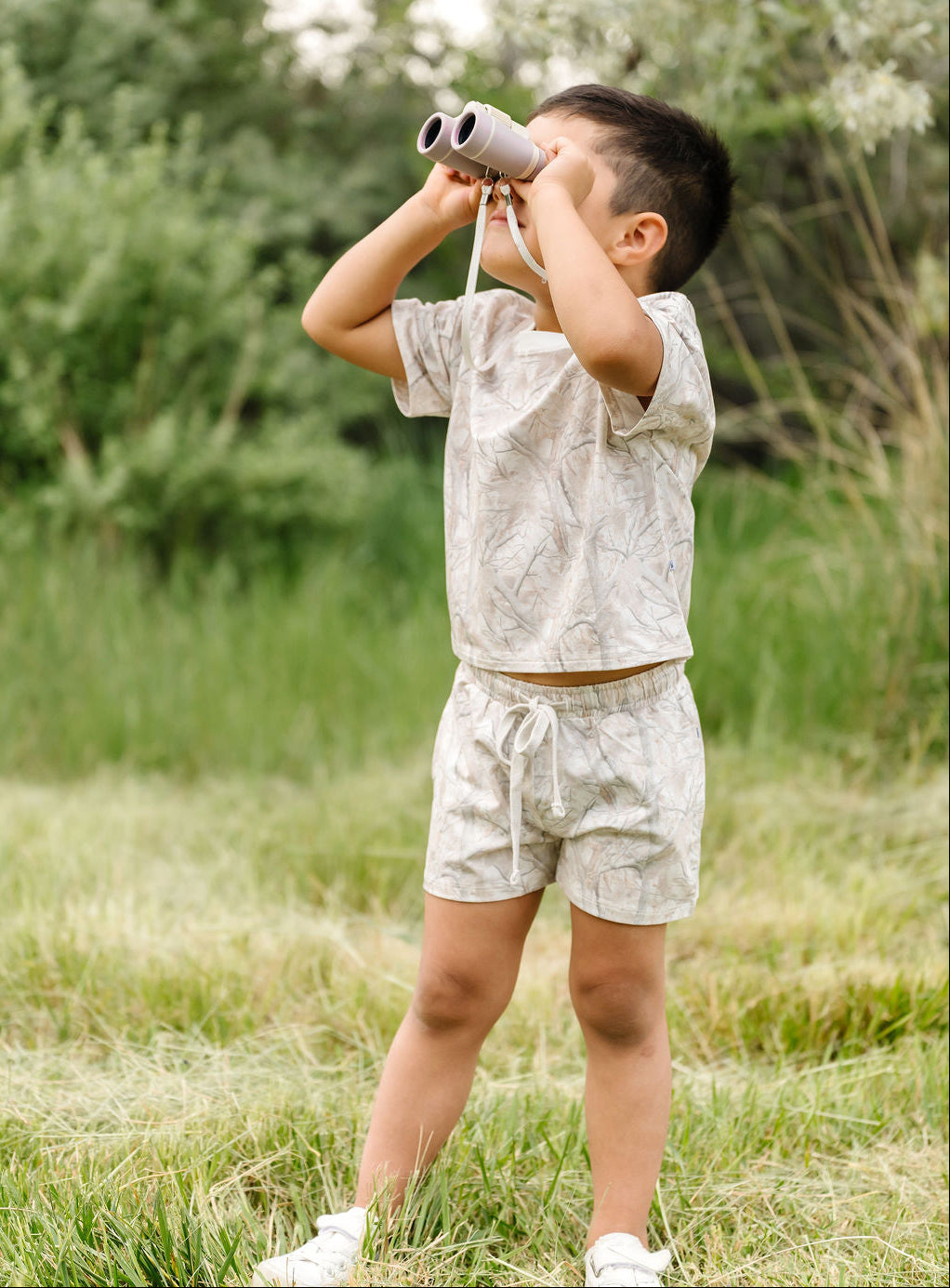 Child playing with binoculars in a grassy outdoor setting