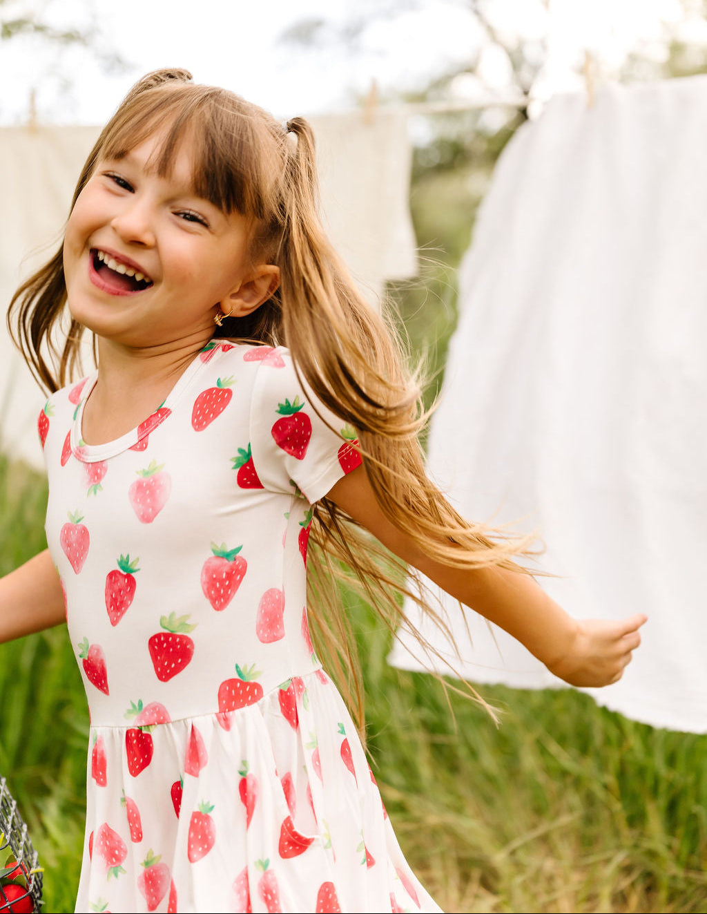 Child in a strawberry dress running outdoors with a blurred background