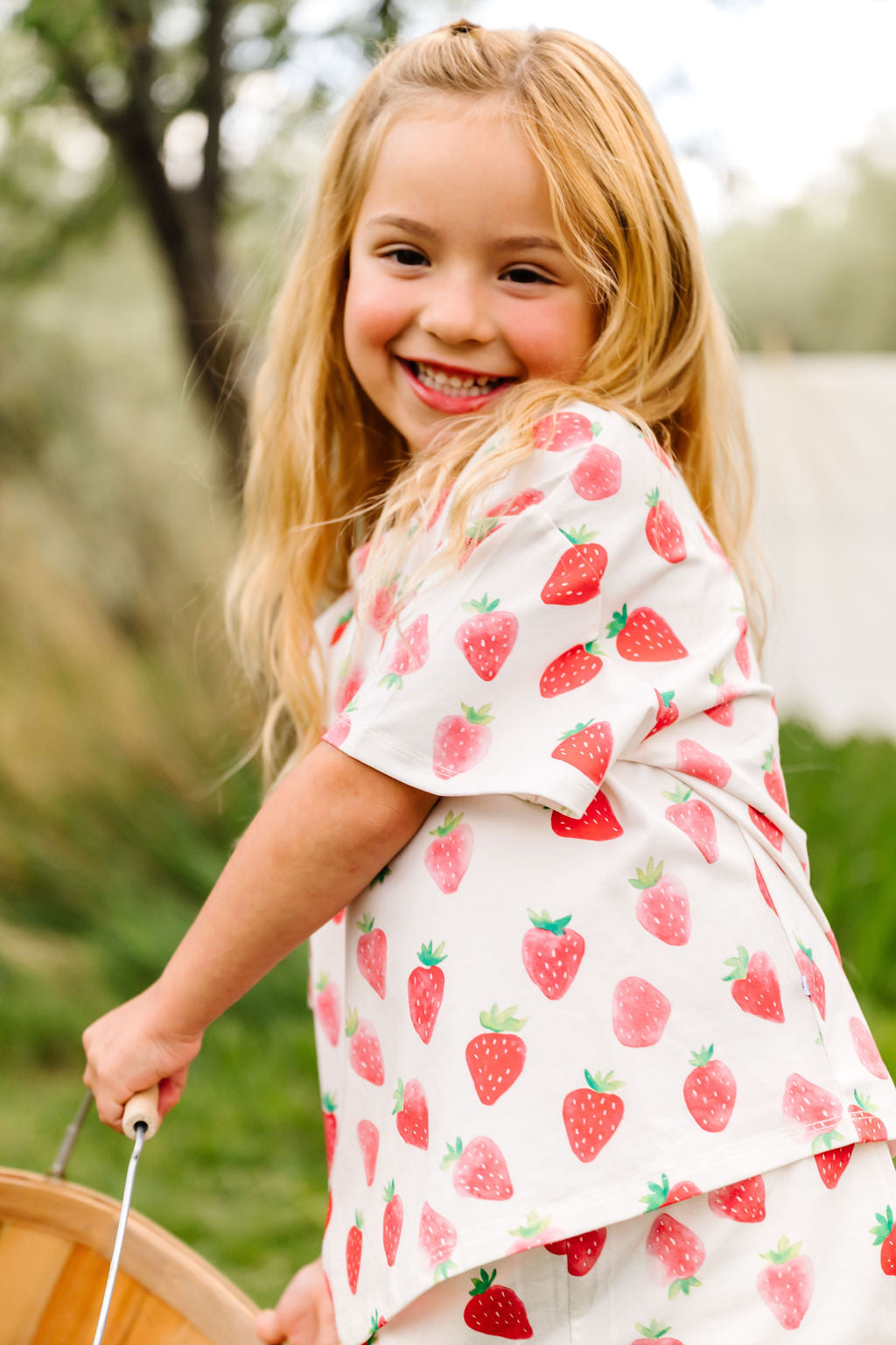 Young girl wearing a strawberry-patterned outfit outdoors