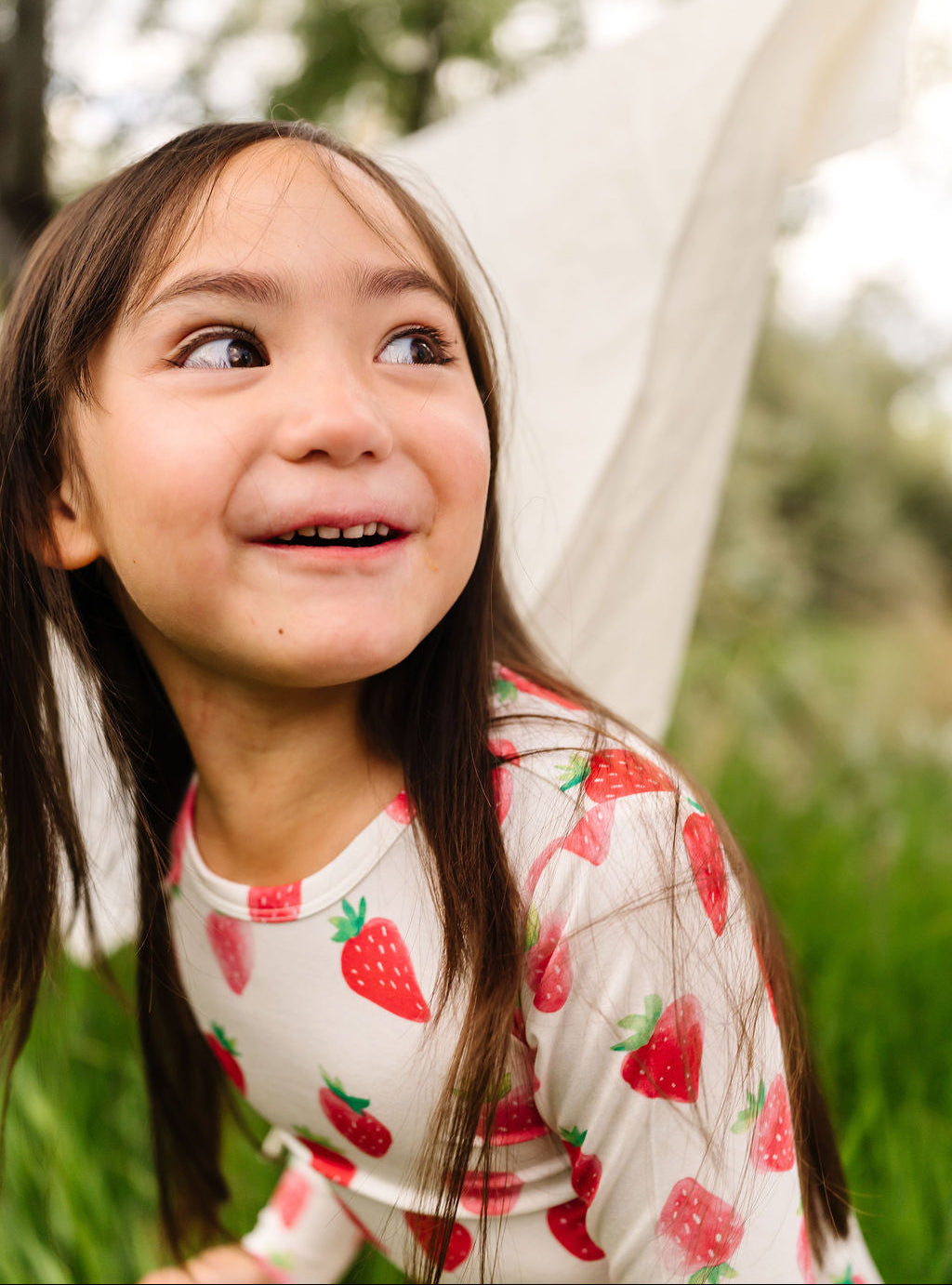 Young girl with strawberry pajamas  looking up outdoors