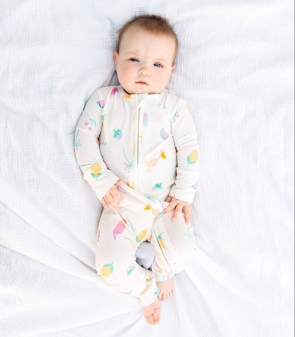 Baby wearing a colorful onesie on a white blanket