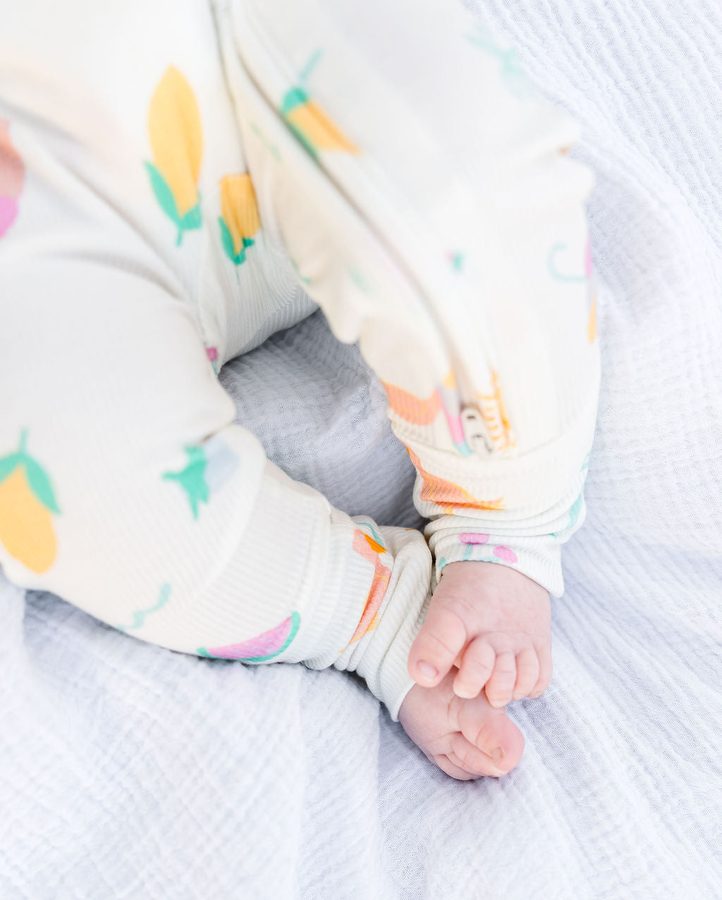 Baby's feet in a colorful patterned outfit on a textured surface