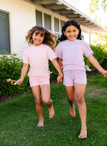 Two young girls running on grass in front of a house