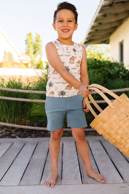 Child holding a woven basket on a wooden deck with greenery in the background