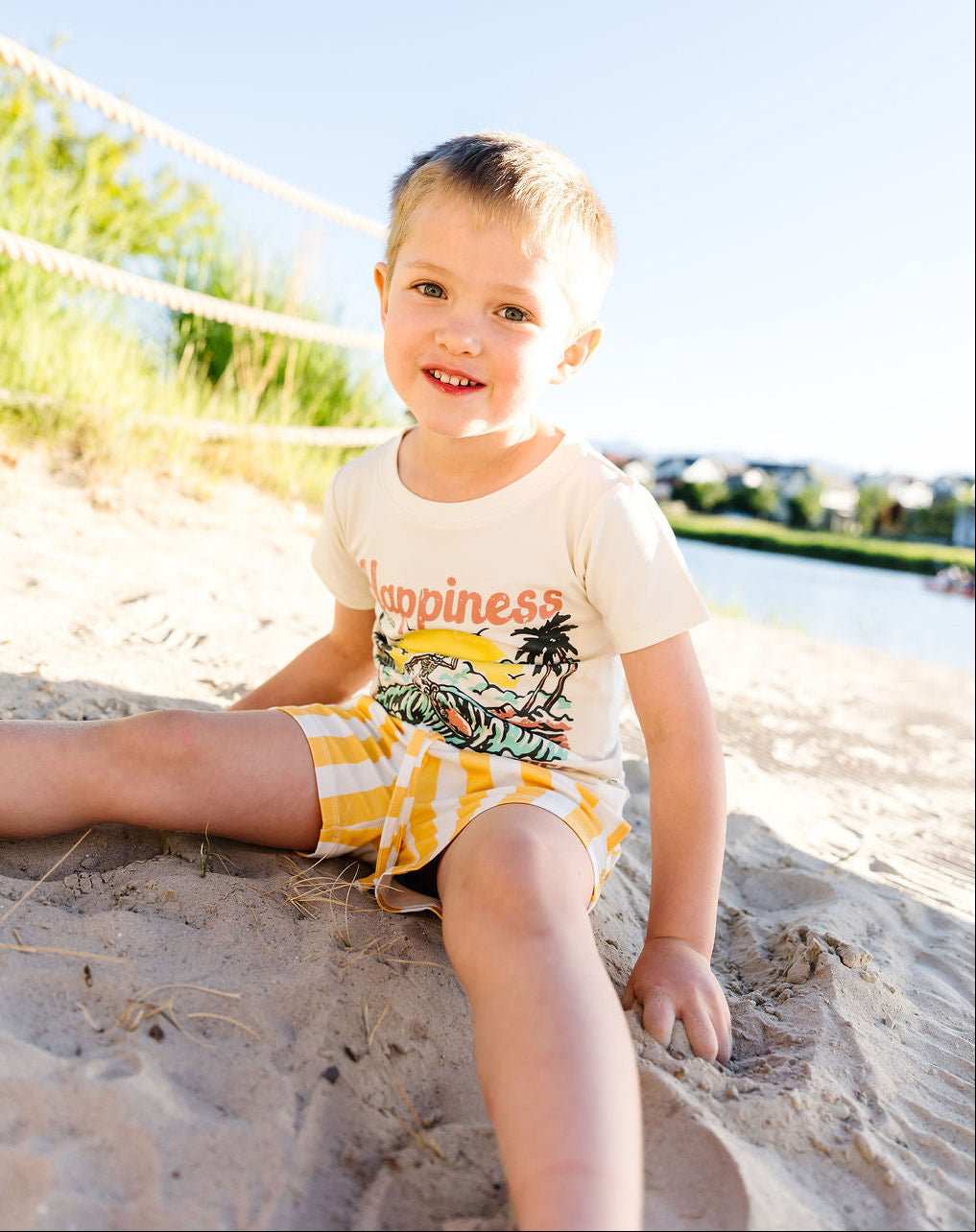 Child sitting on a sandy beach with a clear blue sky