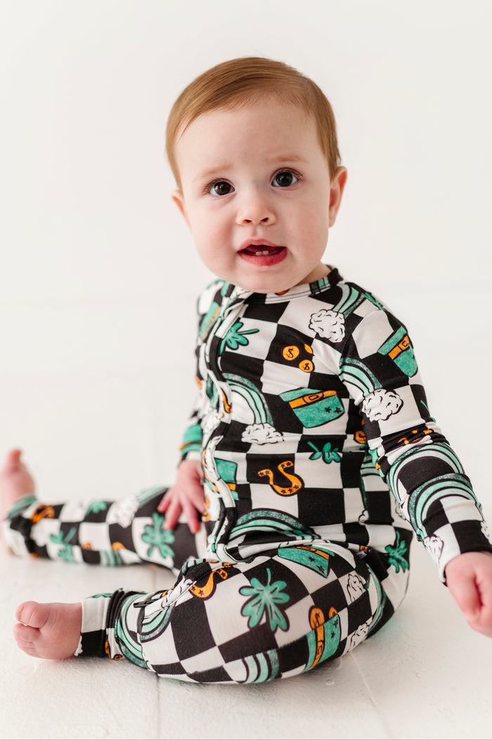 Infant wearing a checkered bamboo zip romper with St. Patrick's Day symbols against a white background 