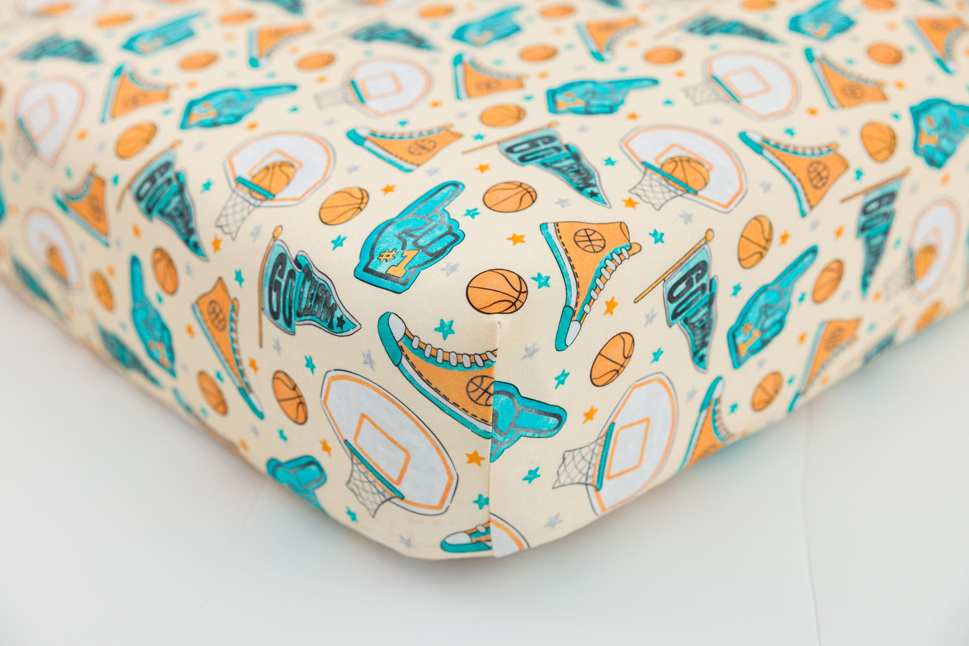 Bamboo crib sheet with sports-themed pattern on a white surface