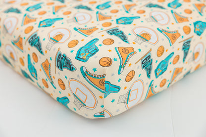 Bamboo crib sheet with sports-themed pattern on a white surface