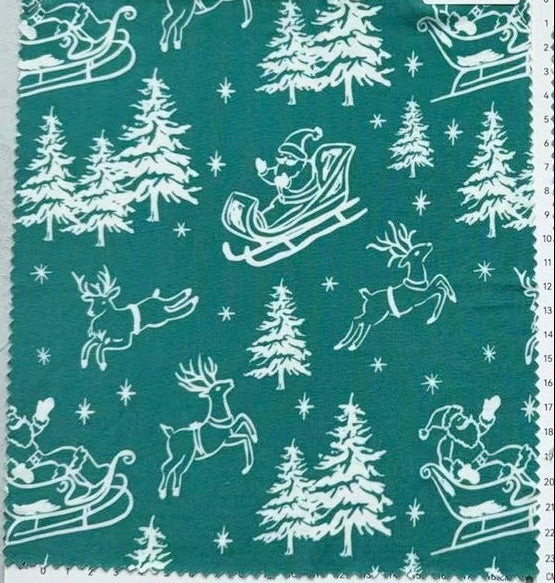 A fabric swatch card from Birdie Bean featuring a festive Christmas print with white silhouettes of Santa Claus in sleighs, reindeer, pine trees, and snowflakes on a teal green background.
