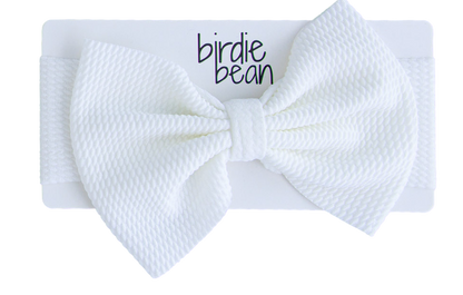 White textured bow headband with 'birdie bean' branding on a white background